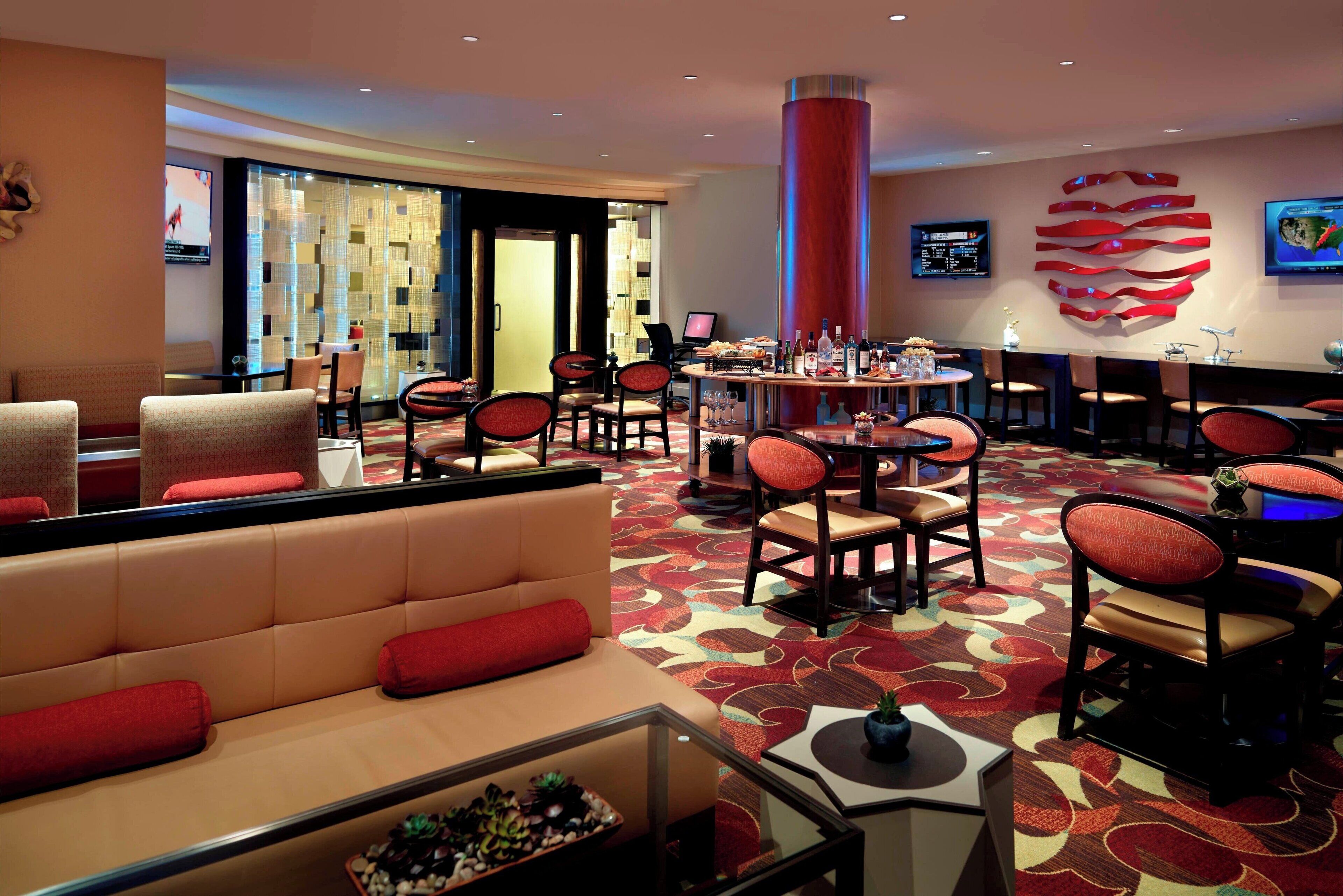 Un vestíbulo de hotel con zona de estar, bar y una columna decorativa grande.