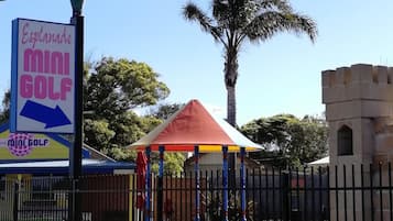Un letrero de mini golf, una palmera y una estructura con forma de castillo.