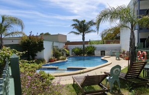 Una piscina al aire libre, sillones reclinables de piscina