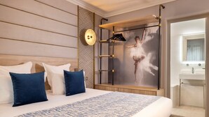 A hotel room with a large bed, a wooden headboard, a wall-mounted mirror, and a ballet dancer artwork. - Hôtel Nude Paris - Color Vision (Paris)