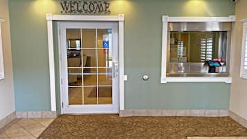 Ein Empfangsbereich mit einem 'WELCOME'-Schild, einem Empfangstresen und einem Fenster mit Blick.