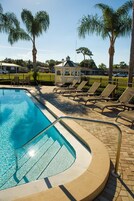 Una piscina al aire libre, sombrillas, sillones reclinables de piscina