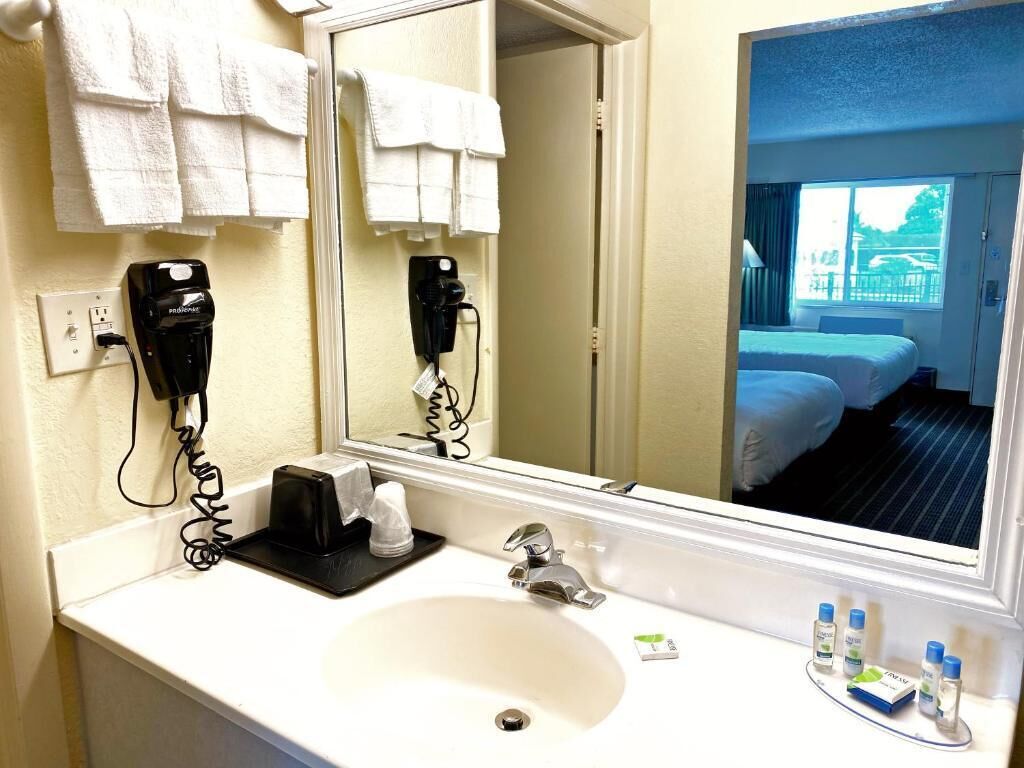 A hotel bathroom with a sink, mirror, and toiletries.