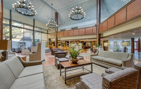A spacious lobby with high ceilings, large windows, and modern furniture.
