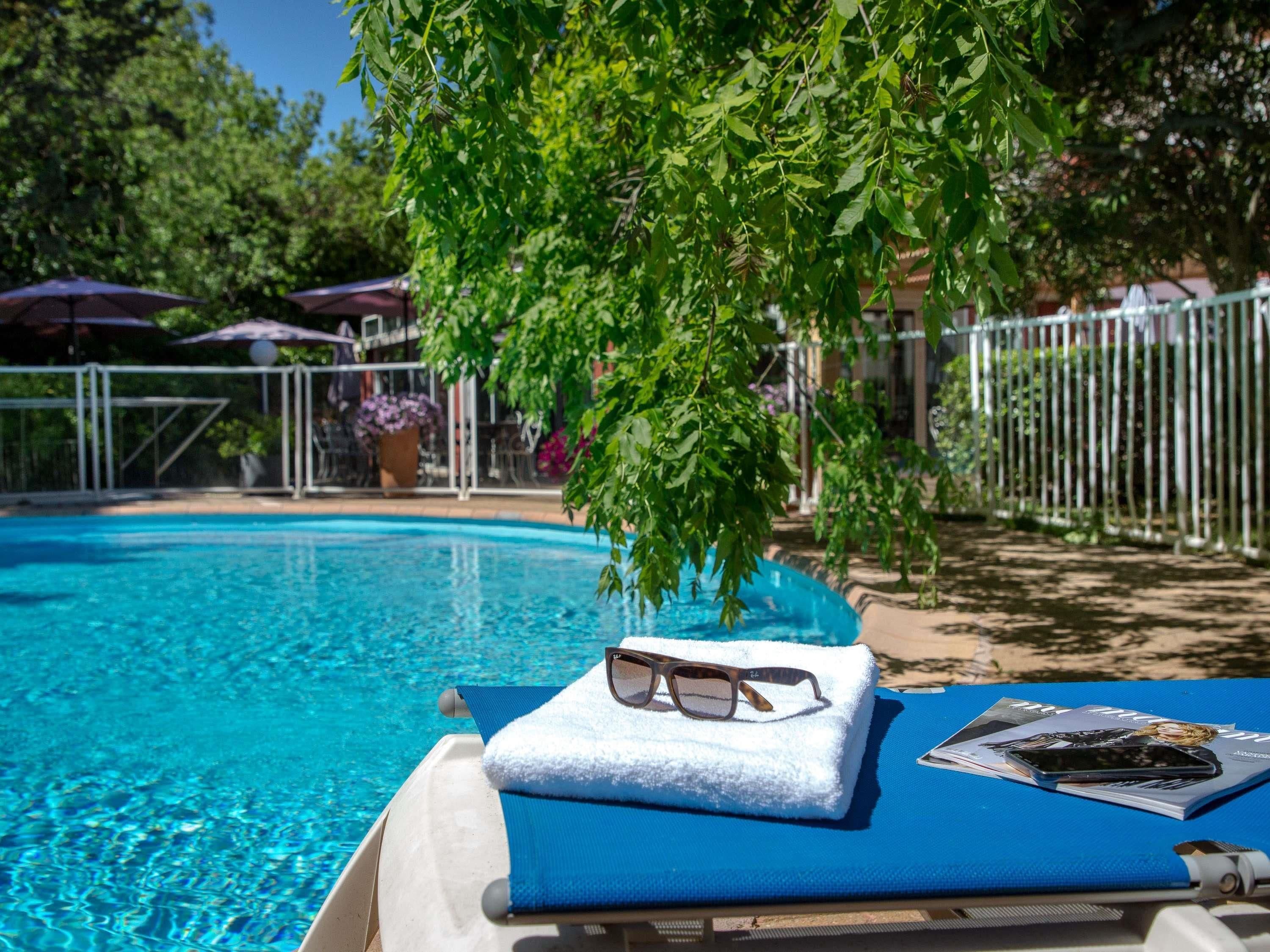 A poolside lounge chair with a towel, sunglasses, and a magazine.