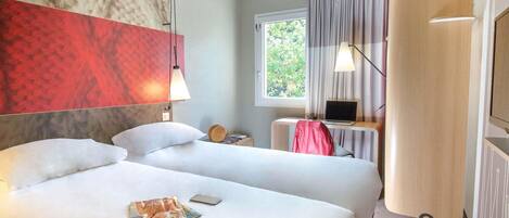 Habitación de hotel con dos camas, un escritorio con una computadora portátil, una ventana con cortinas y una alfombra roja.