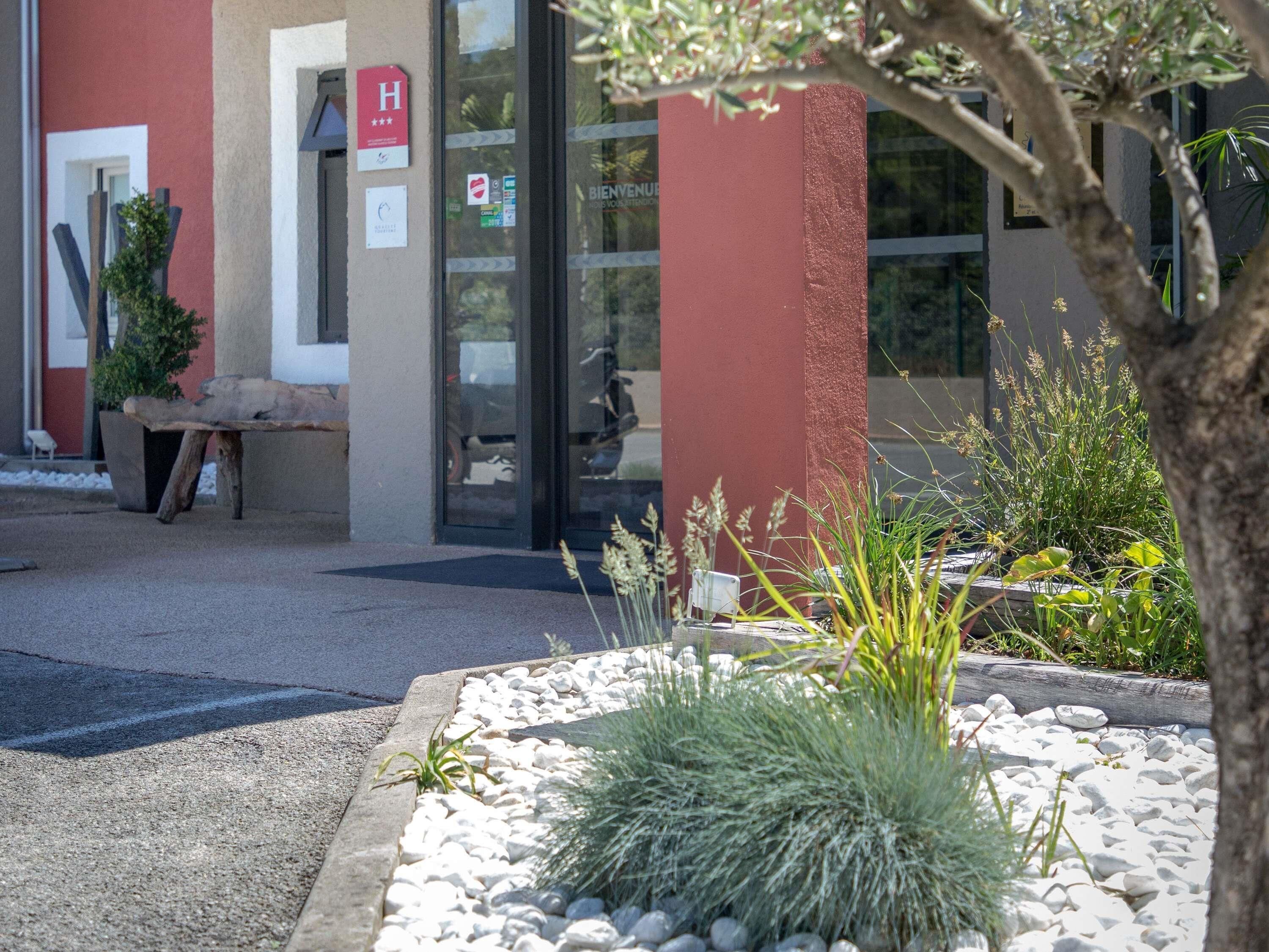 A building entrance with a red pillar, a wooden bench, and a sign indicating a hotel.