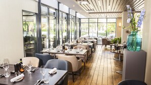 A restaurant with wooden flooring, large windows, and tables set for dining. - Bilderberg Garden Hotel (Amsterdam)