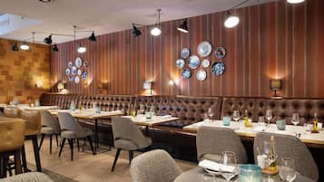 A restaurant with a wooden wall, multiple dining tables, and chairs.