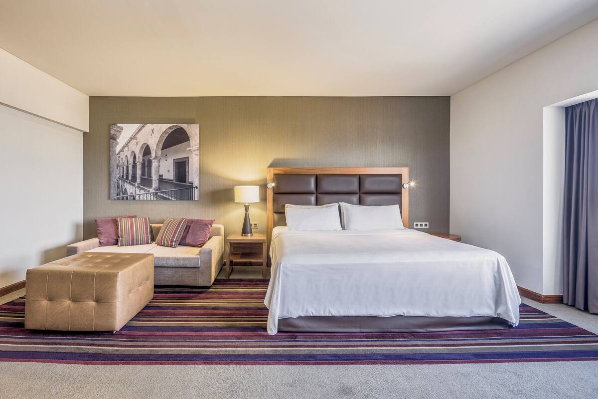 Een hotelkamer met een groot bed, een bank, een tafeltje en een decoratief wandobject.