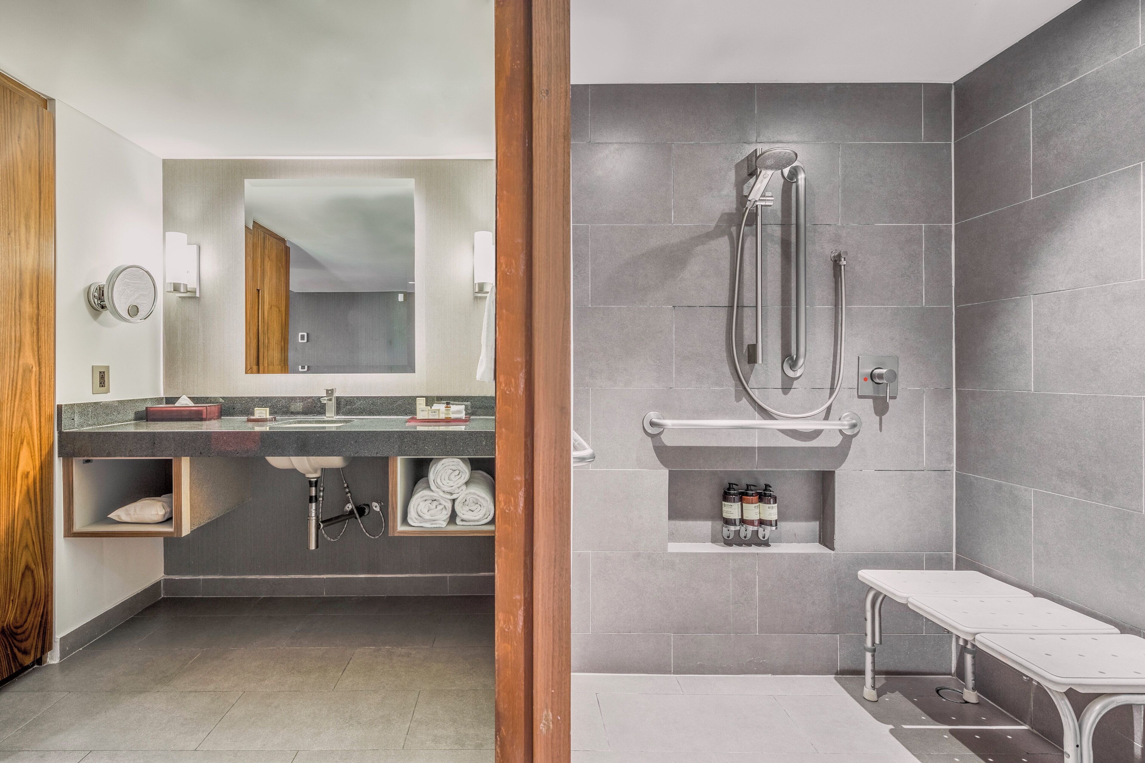 Une salle de bain moderne dotée d’un meuble-lavabo à deux vasques, d’un grand miroir et d’un espace douche avec un pommeau de douche à main.