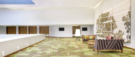 Una habitación amplia con alfombra estampada, una larga barra blanca, armarios de madera, un televisor y un mural grande en la pared.