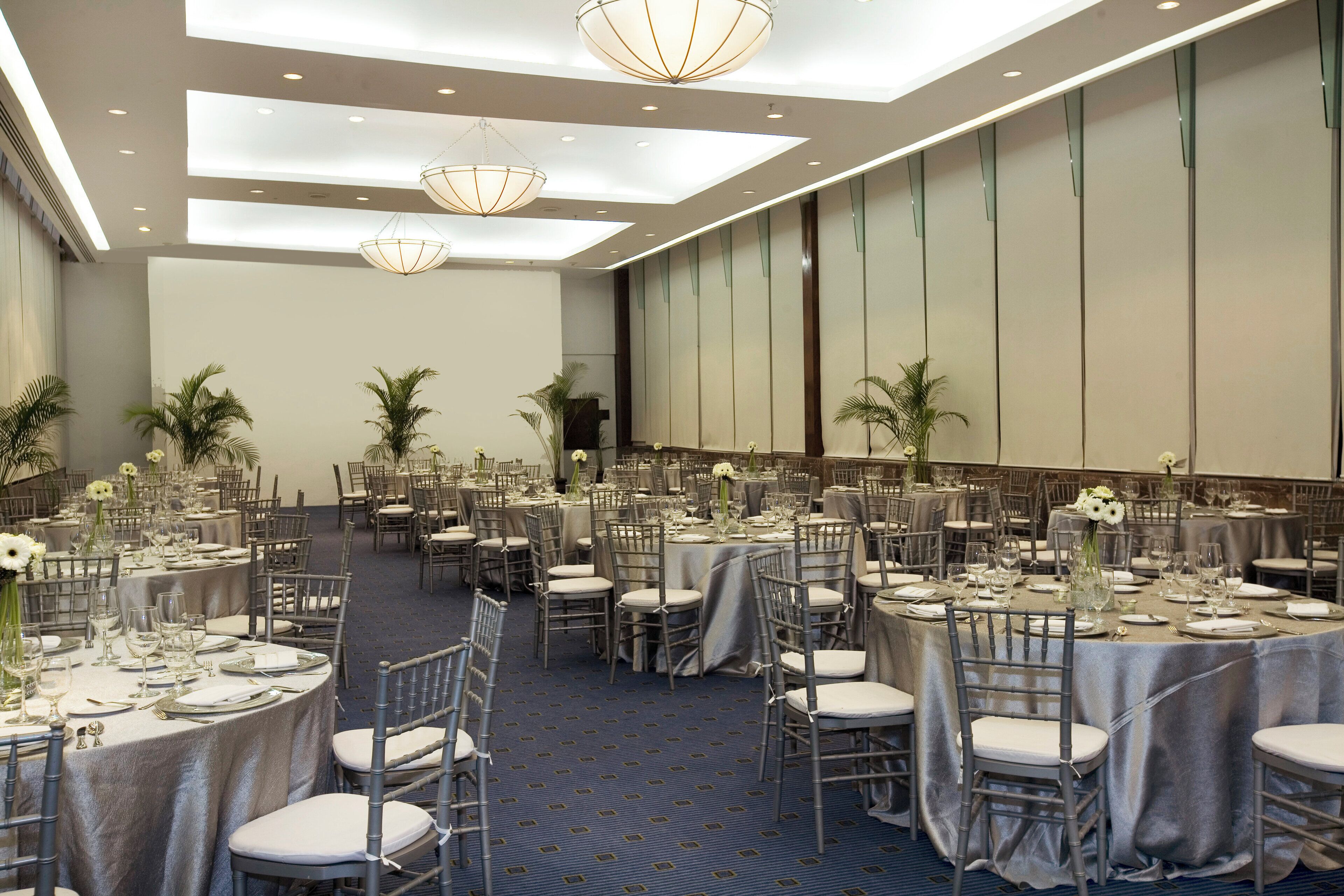 A banquet hall with round tables set for dining, each with white tablecloths and silverware.