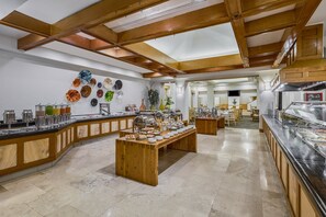 Enjoy a meal in our well-appointed buffet area with a high ceiling and skylight, surrounded by glass display cases and decorative plates.