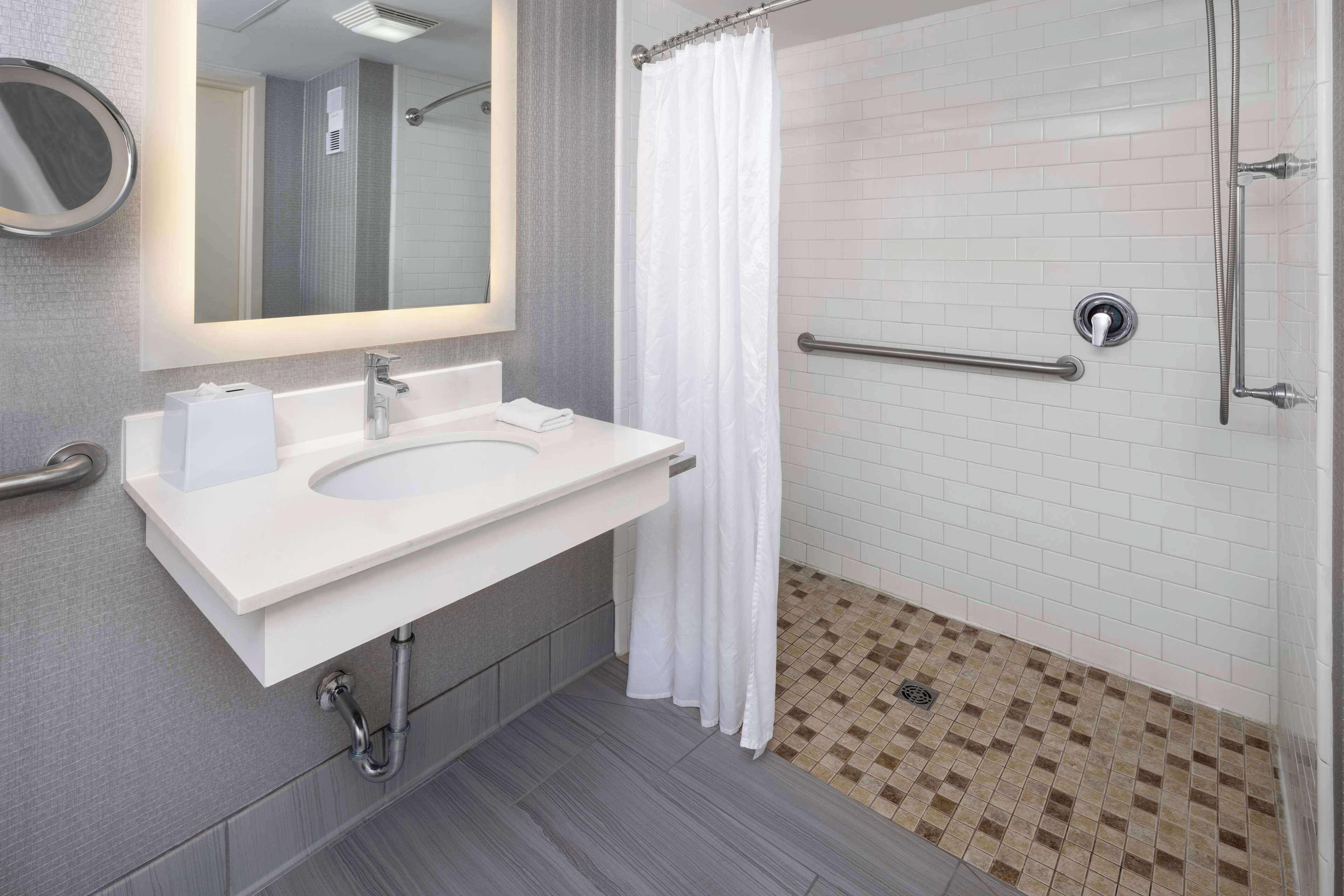 Une salle de bain moderne avec un lavabo blanc, un miroir et un espace douche.