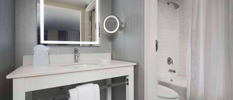A bathroom with a white sink, mirror, and toilet.