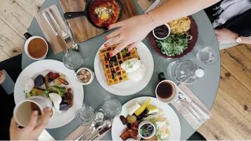 A round table with various breakfast items including waffles, eggs, and salads.