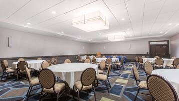 A conference room with round tables and chairs, a patterned carpet, and a modern ceiling design.