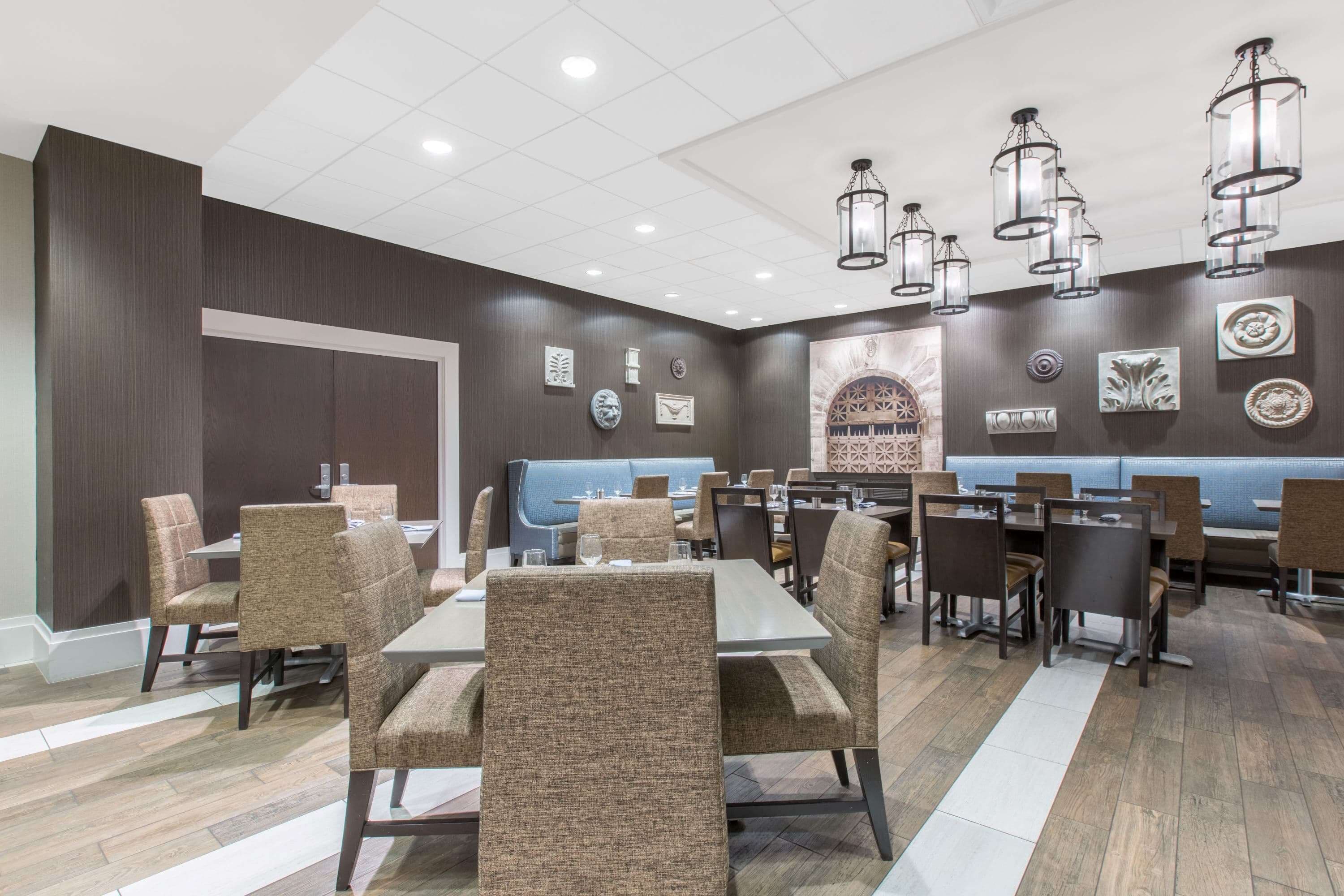 A restaurant with multiple tables and chairs, a blue booth seating area, and decorative wall art.