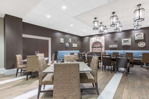 Un restaurante con varias mesas y sillas, un área de asientos tipo banqueta azul y decoración en las paredes.