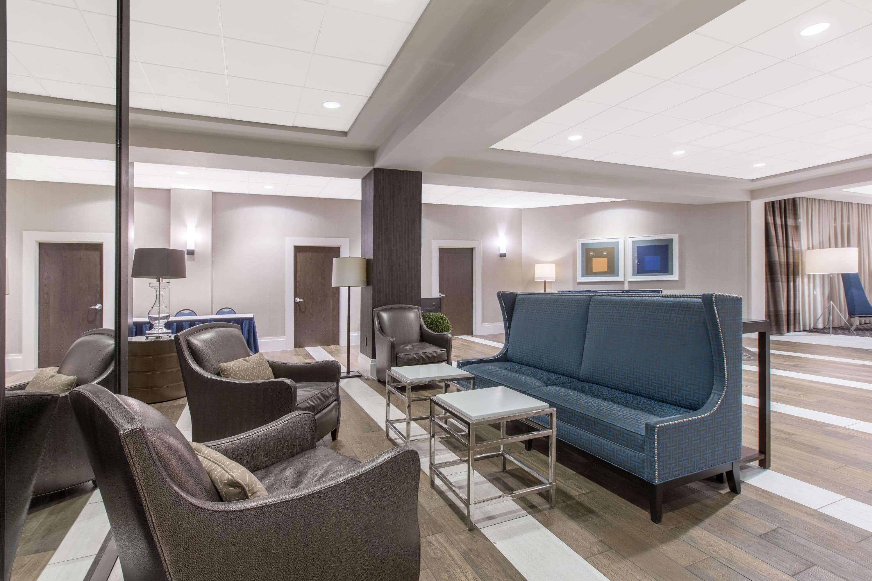 A modern hotel lobby with leather sofas, a blue patterned sofa, and a small table.
