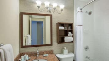 A bathroom with a sink, mirror, towel rack, shower, and a shelf with towels.