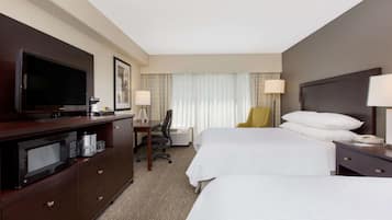 A hotel room with two beds, a desk, a television, and a minibar.