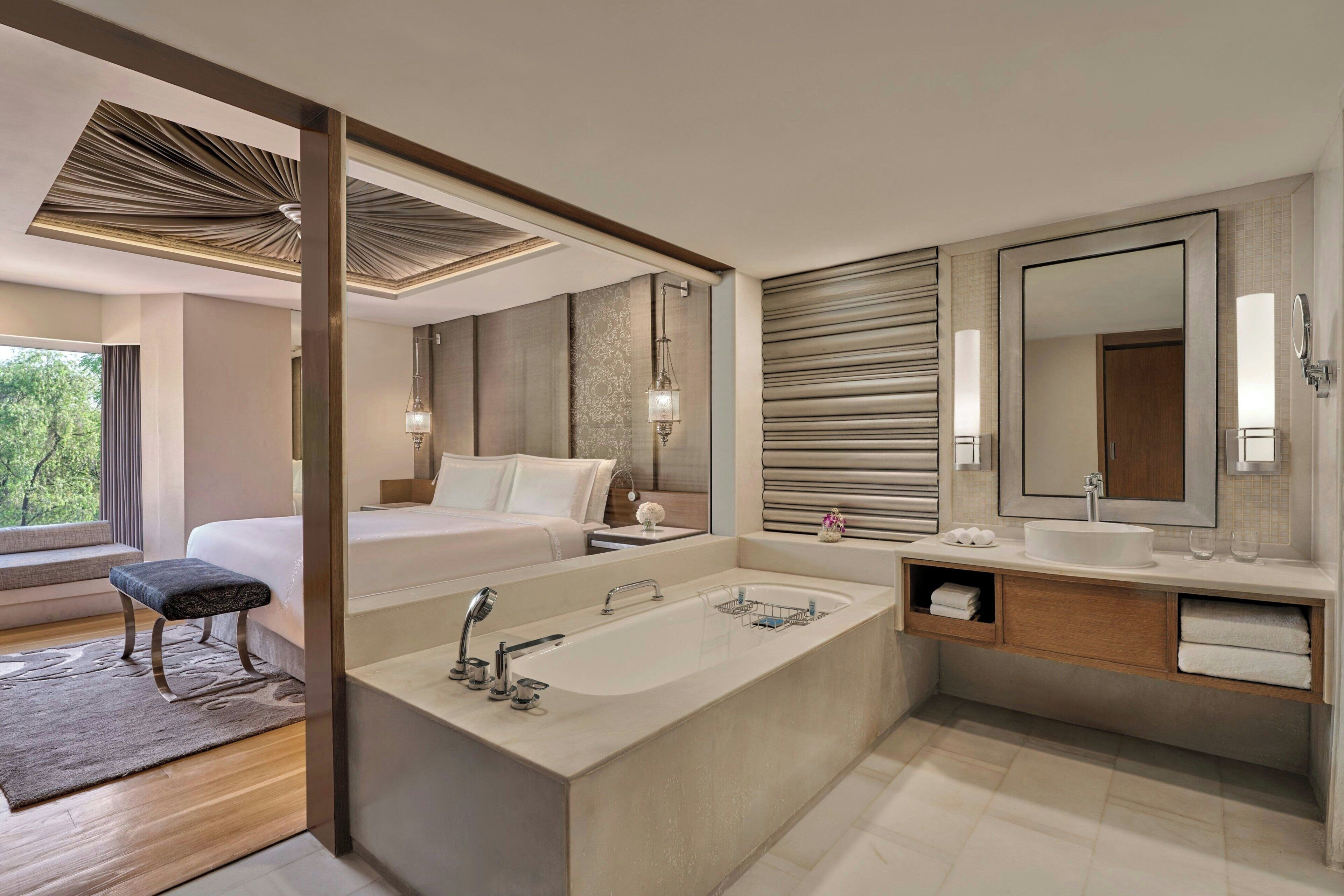 A modern hotel bathroom with a large bathtub, a separate shower area, and a vanity with a mirror.