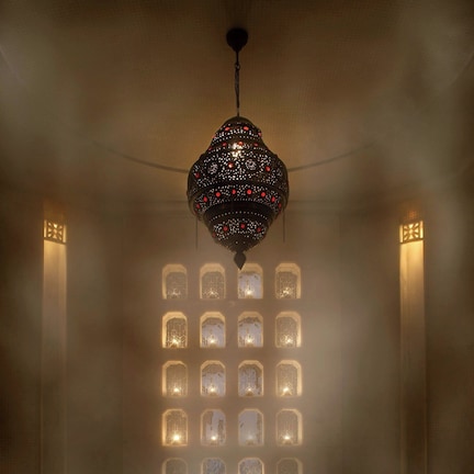 A room with a large, ornate chandelier, a wall of illuminated windows, and a reflective marble floor.