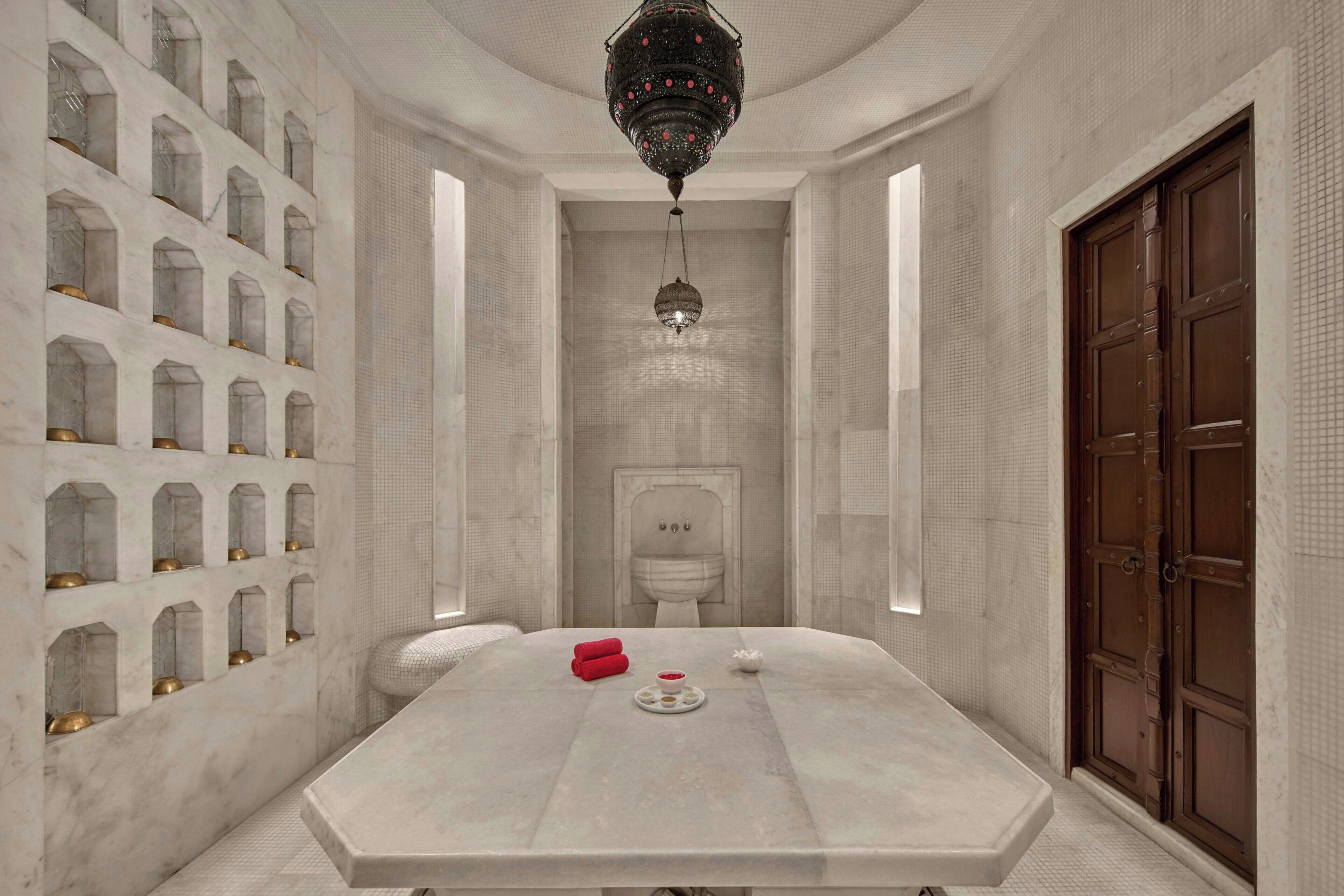 A room with a large marble table, a chandelier, and a large wooden door.
