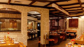 A restaurant with stone walls, wooden beams, and a long dining table set for a meal.