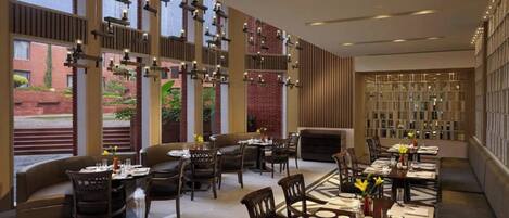 A modern restaurant with high ceilings, exposed brick walls, and a variety of seating options including tables and booths.