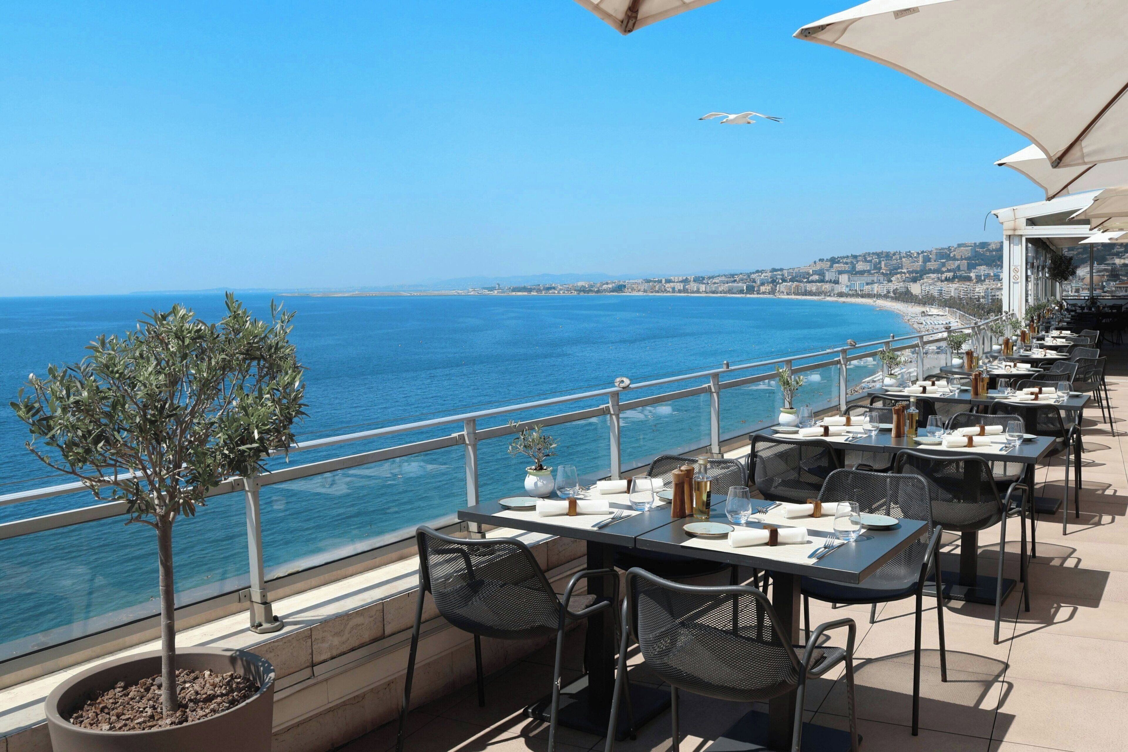 Restaurante frente al mar con terraza al aire libre, que ofrece mesas, sillas y sombrillas.