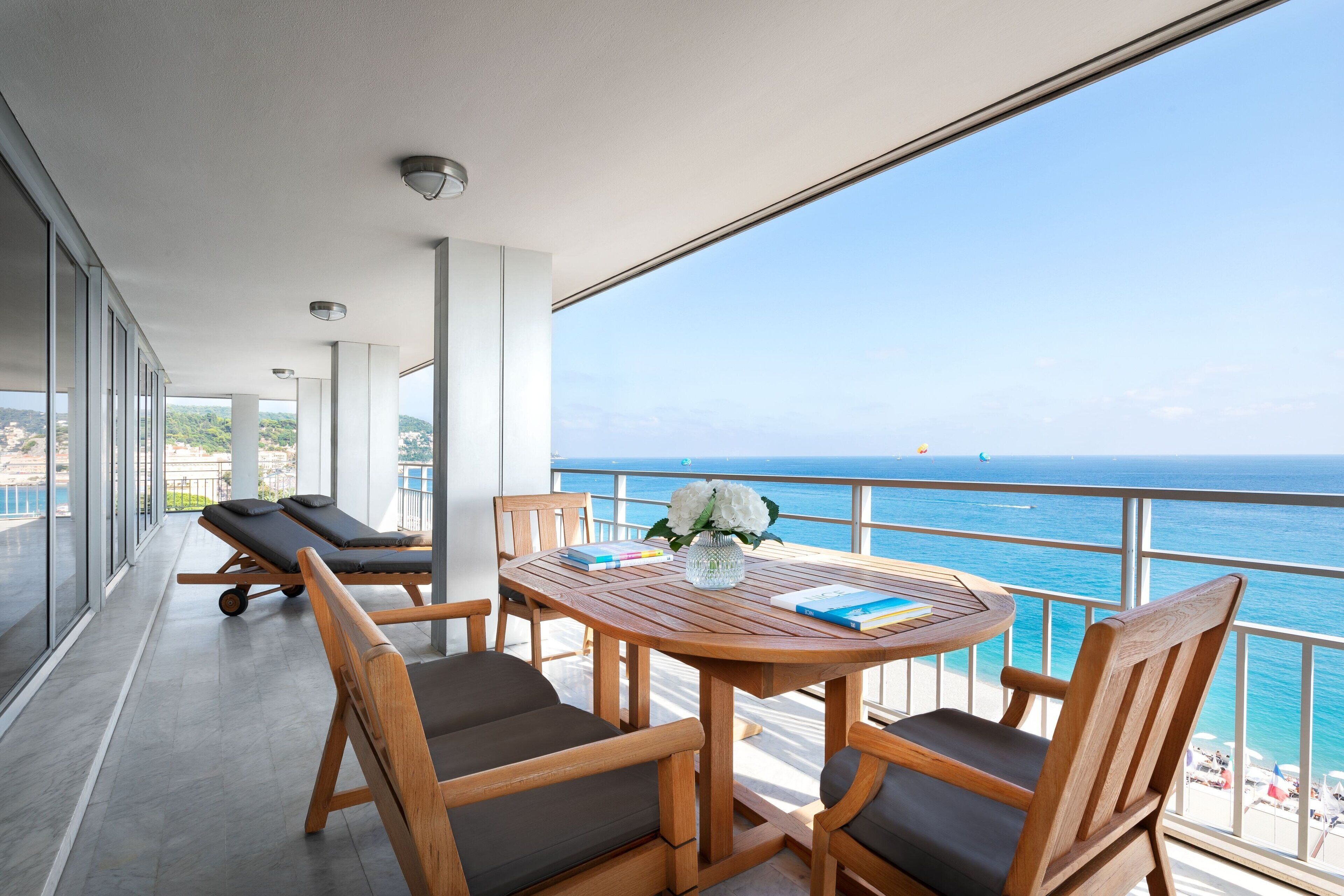 Ein Balkon mit Holztisch, Stühlen und einem Massagesessel.