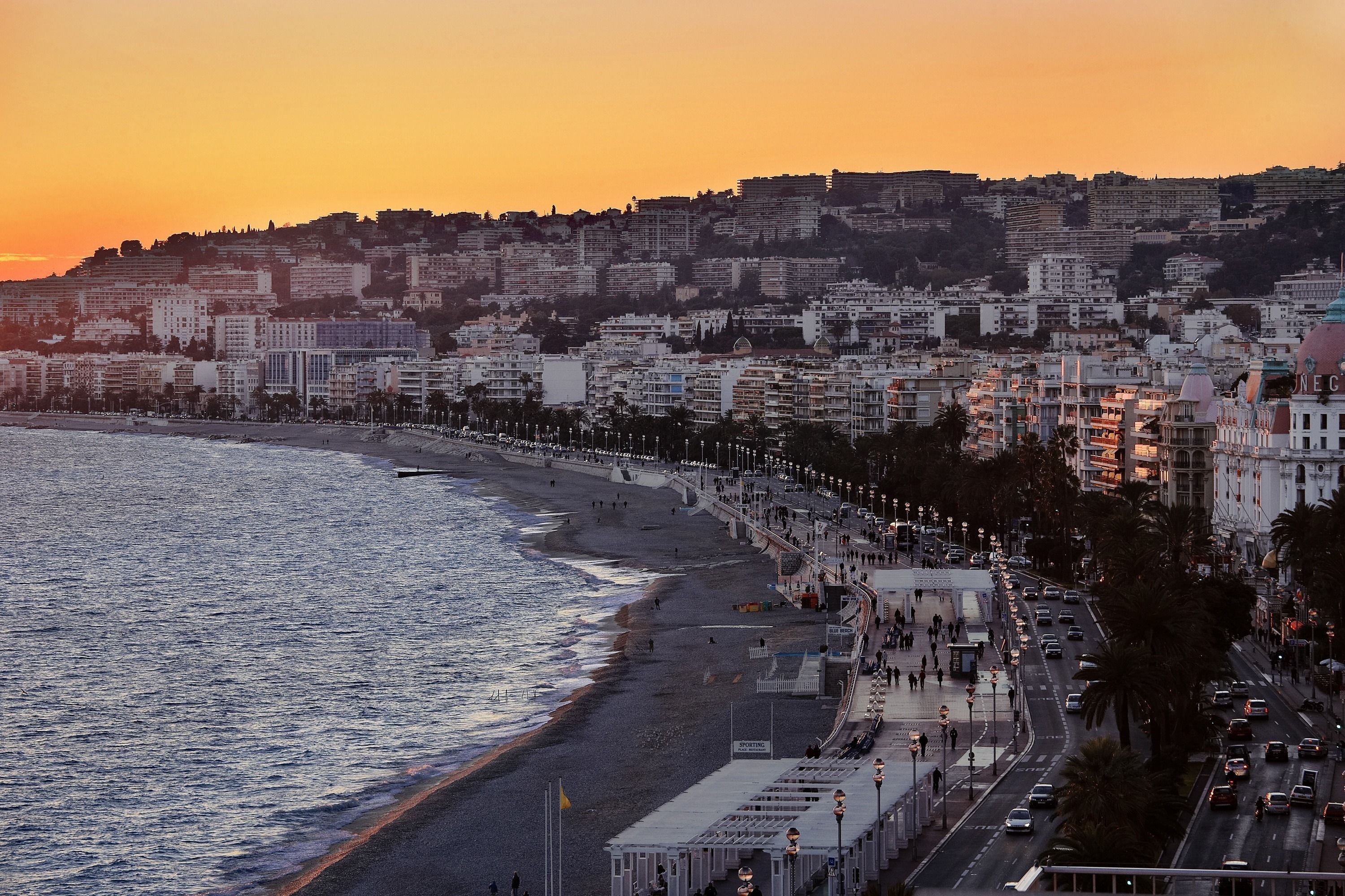 Un paysage urbain côtier avec une plage, une promenade et des bâtiments le long du littoral.