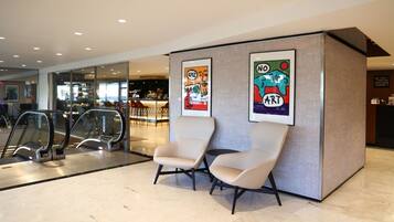 Una hall moderna con scale mobili, zone relax e opere d'arte alle pareti.