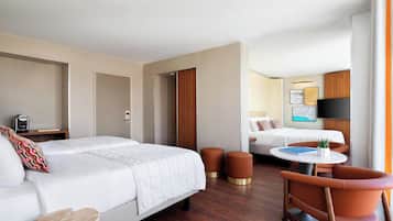 Habitación de hotel con cama, escritorio con silla, mesita con planta y televisor.