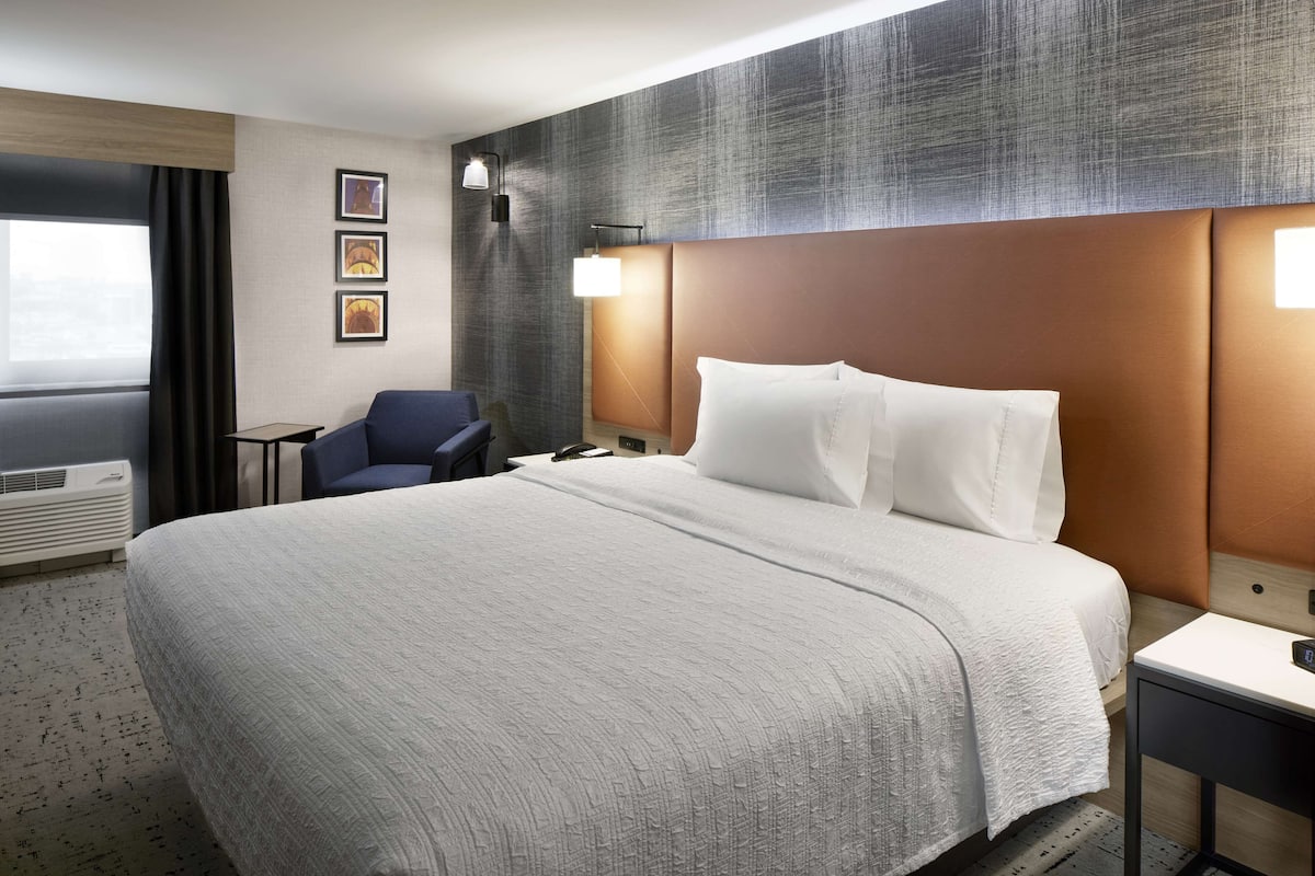 Ein Hotelzimmer mit einem großen Bett, einem Schreibtisch, einem Stuhl und einer Wandlampe.