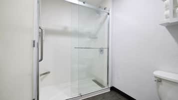 A glass-enclosed shower with a white toilet and a towel rack.