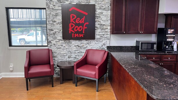 A modern kitchen with a stone backsplash, a Red Roof Inn sign, and a view of a parked vehicle outside. - Red Roof Inn Rockingham (Rockingham)