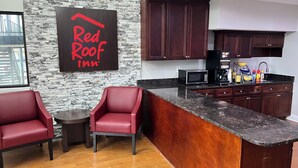 A modern kitchen with dark wooden cabinets, a granite countertop, and a Red Roof Inn sign on the wall. - Red Roof Inn Rockingham (Rockingham)