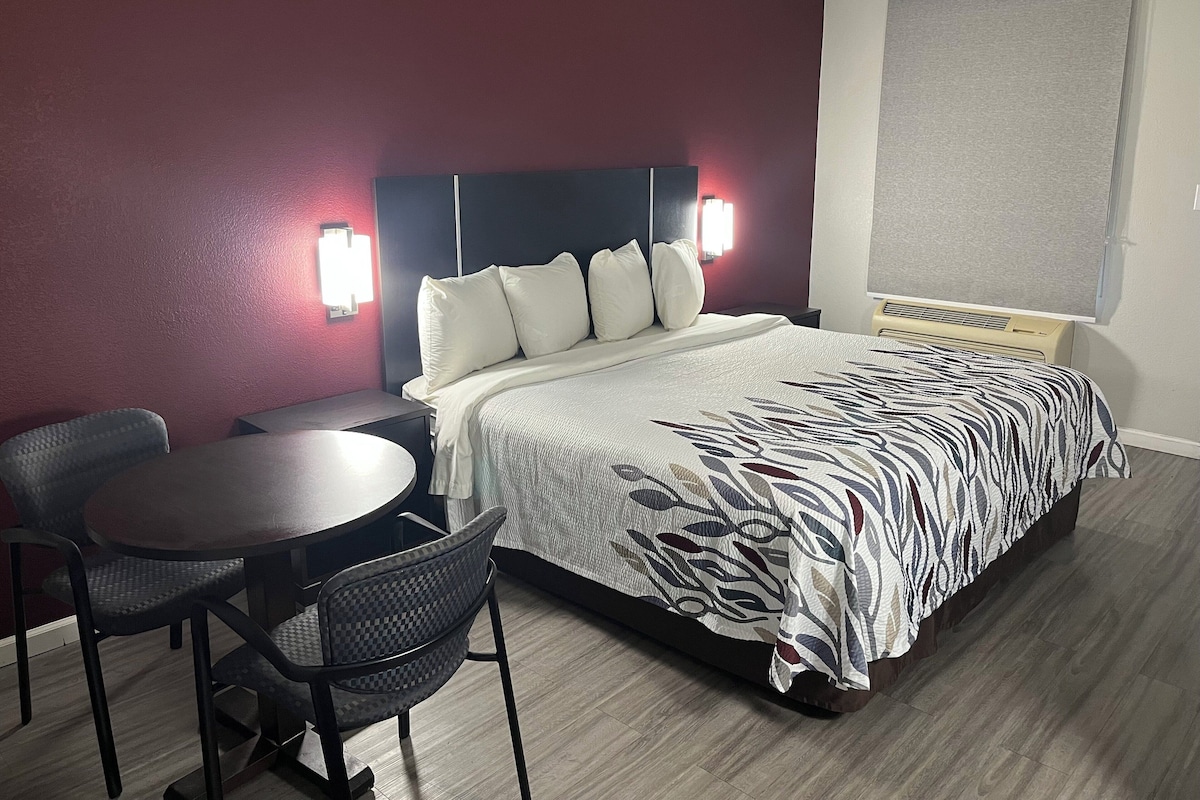 Una habitación de hotel con una cama, un escritorio y dos sillas.