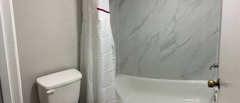 Un baño con inodoro, cortina de ducha y bañera.