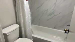 A bathroom with a toilet, a shower curtain, and a bathtub.