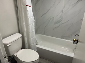 A bathroom with a toilet, a shower curtain, and a bathtub.