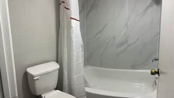 Un baño con inodoro, cortina de ducha y bañera.