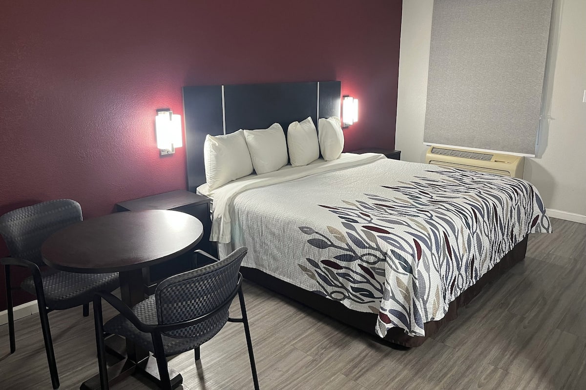 A hotel room with a bed, a desk, and two chairs.