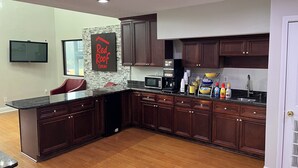 A modern kitchen with dark wood cabinets, a granite countertop, a built-in microwave, and a coffee maker. - Red Roof Inn Rockingham (Rockingham)