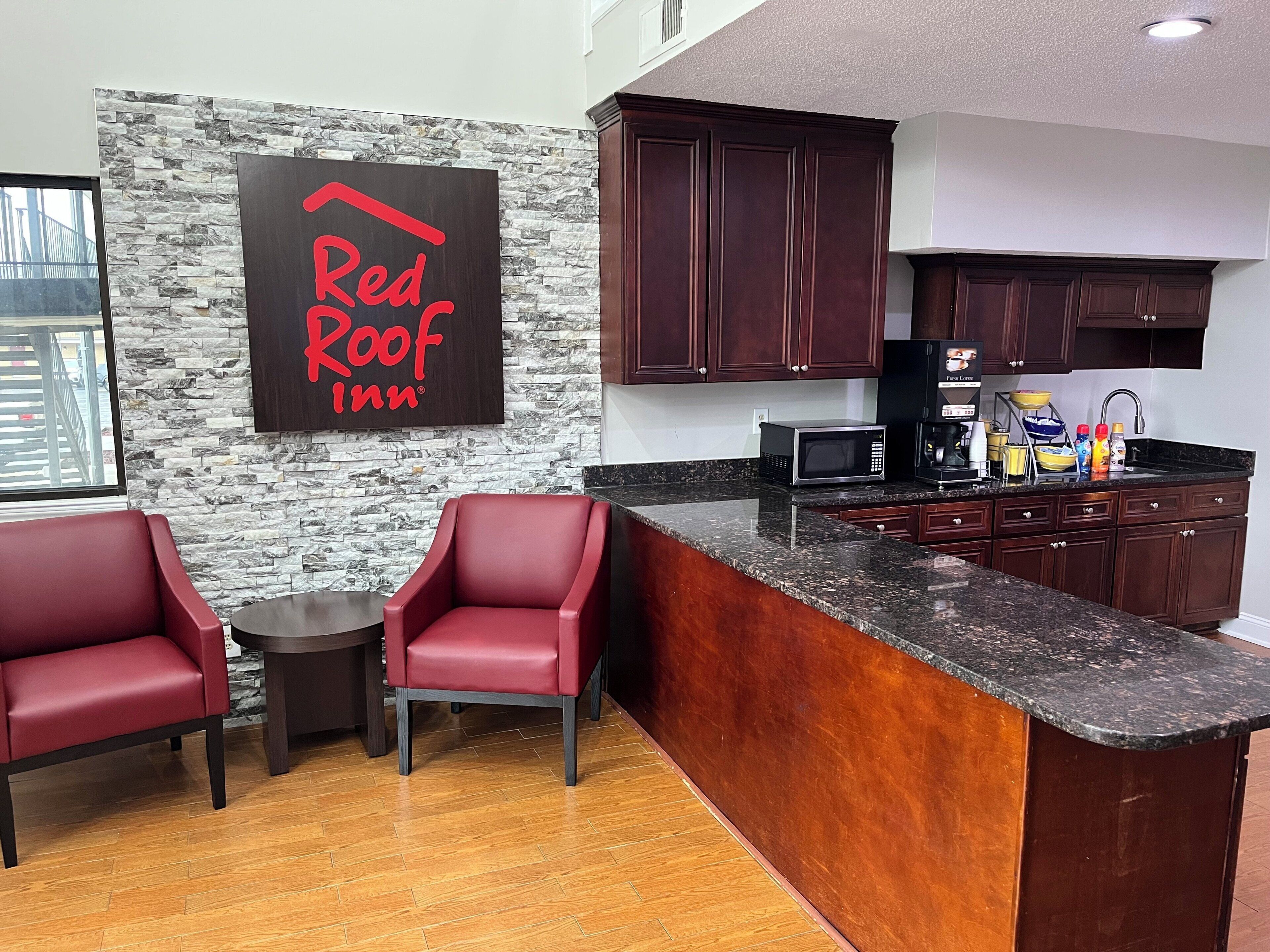 Eine moderne Küche mit dunklen Holzausziehtüren, einer Granitarbeitsplatte und einem Red Roof Inn Schild an der Wand.