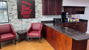 Eine moderne Küche mit dunklen Holzausziehtüren, einer Granitarbeitsplatte und einem Red Roof Inn Schild an der Wand.